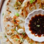 Close-up of a flaky scallion pancake showing crisp golden layers and fresh scallions