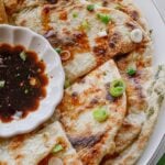 Golden scallion pancakes cut into wedges and arranged on a serving platter