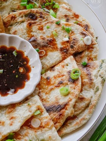Golden scallion pancakes cut into wedges and arranged on a serving platter