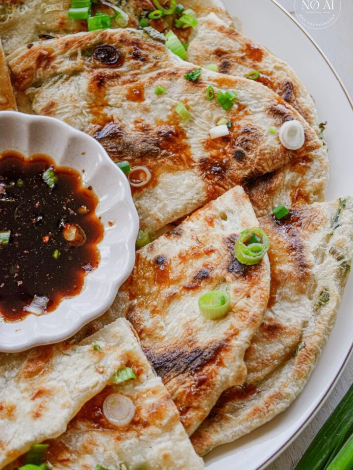 Golden scallion pancakes cut into wedges and arranged on a serving platter
